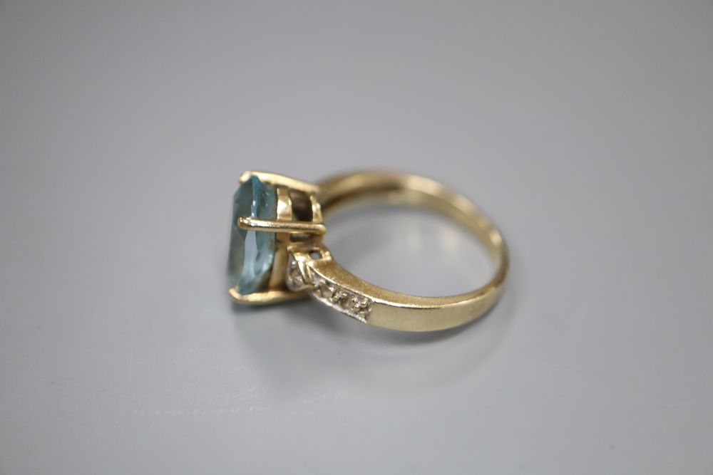 A modern 9ct gold, blue topaz and gem set dress ring, size N, gross 4 grams.